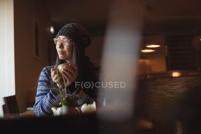 Удумлива жінка має чашку кави в кафе — стокове фото