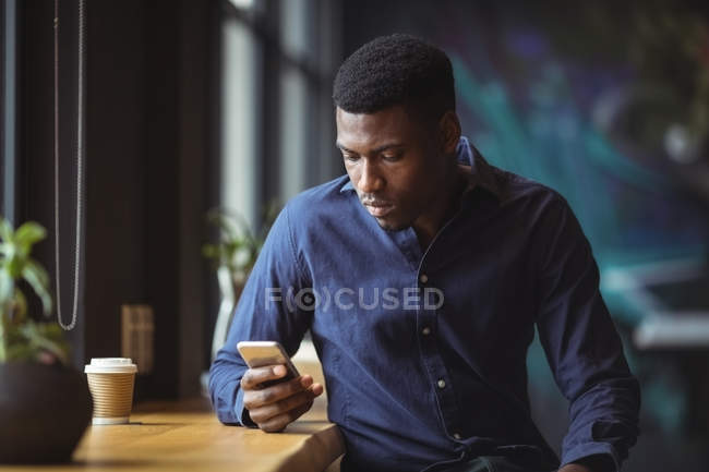 Бизнесмен, использующий мобильный телефон в офисном кафе — стоковое фото