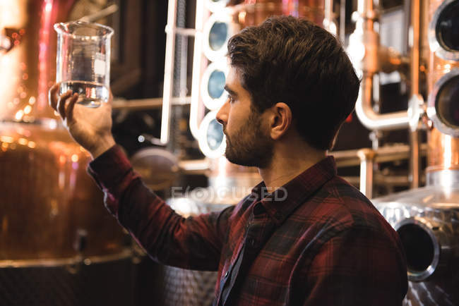 Homme examinant un échantillon d'alcool dans une usine de bière — Photo de stock