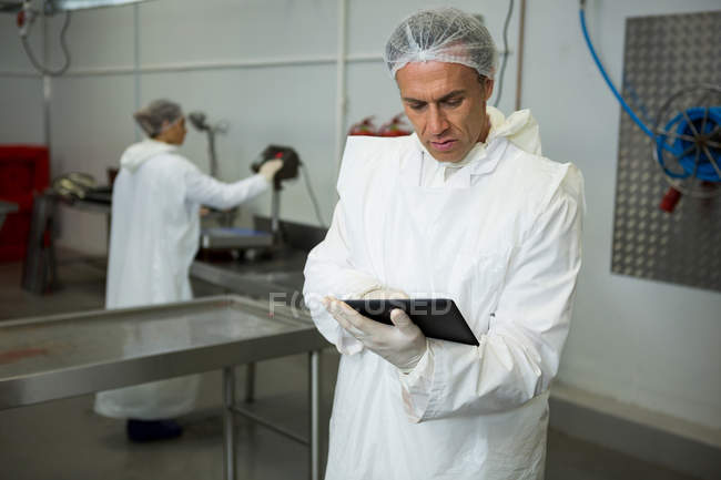 Técnico usando tableta digital en la fábrica de carne - foto de stock