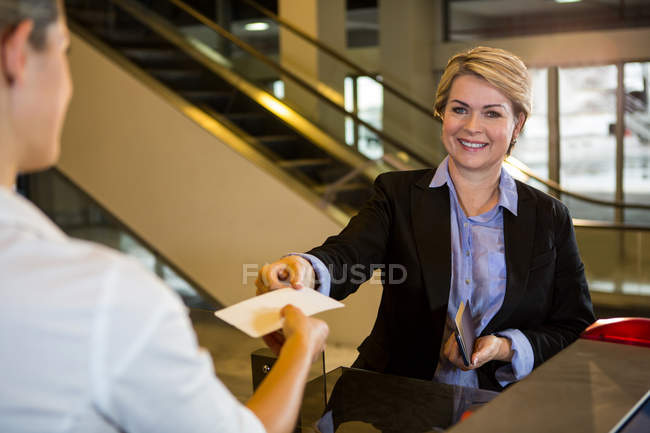 Donna d'affari che mostra la carta d'imbarco al banco del check-in in aeroporto — Foto stock