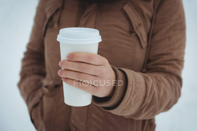 Partie médiane de la femme en veste chaude tenant tasse de café pendant l'hiver — Photo de stock