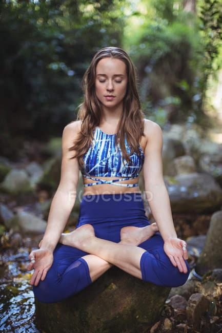 Mulher meditando na posição de lótus na floresta — Fotografia de Stock