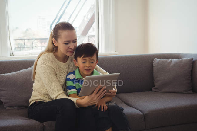 Mother and son using digital tablet in living room at home — Stock Photo