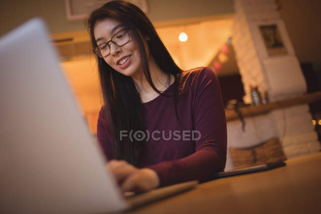 Жінка використовує ноутбук на столі у вітальні вдома — стокове фото