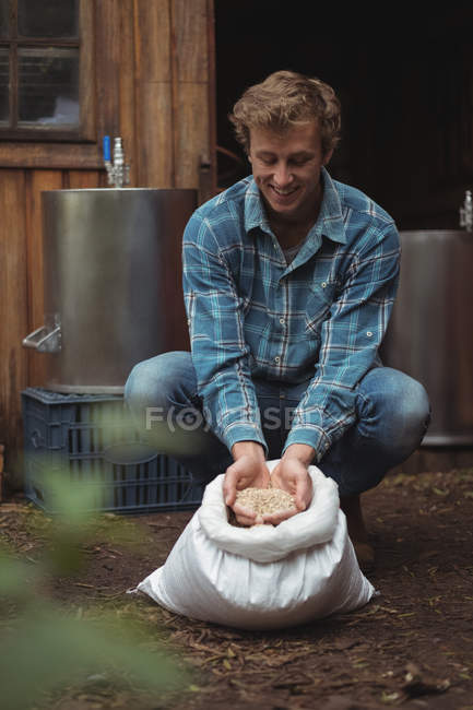 Чоловік тримає мішок з ячменю, щоб приготувати пиво вдома — стокове фото