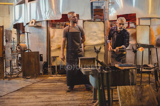 Squadra di soffiatore di vetro che modella un vetro fuso presso la fabbrica di soffiaggio del vetro — Foto stock