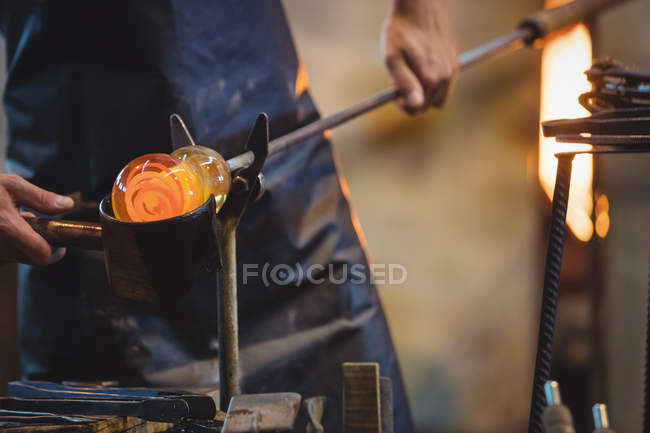 Close-up of glassblower forming and shaping a molten glass at glassblowing factory — Stock Photo