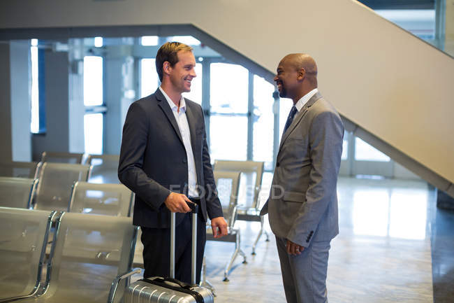 Geschäftsleute interagieren miteinander im Wartebereich am Flughafen — Stockfoto