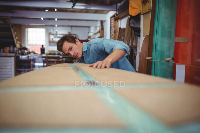 Young man making surfboard in workshop — Stock Photo