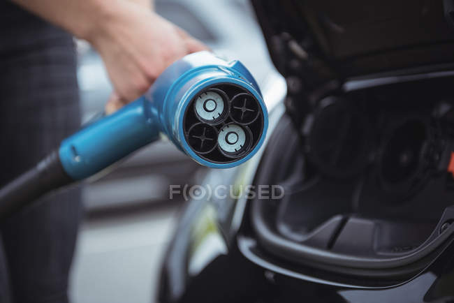 Mid section of woman holding car charger — Stock Photo