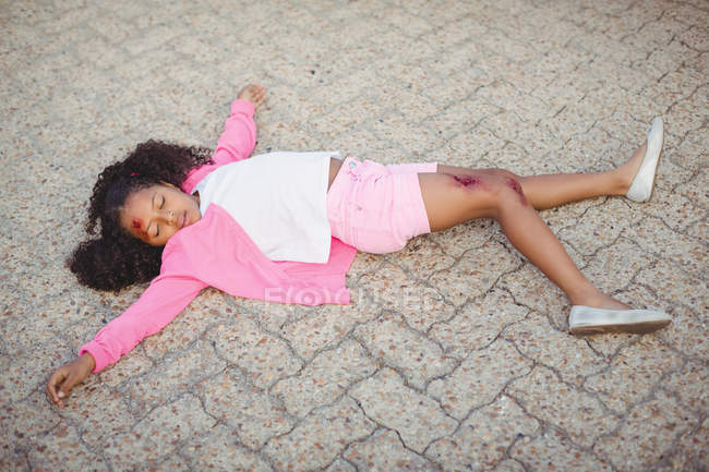 Крупный план бессознательной девушки, упавшей на землю после аварии — стоковое фото