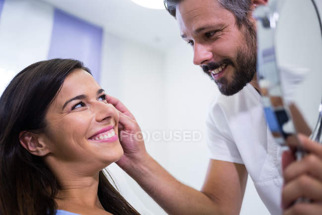 Врач проверяет кожу пациента после косметического лечения в клинике — стоковое фото