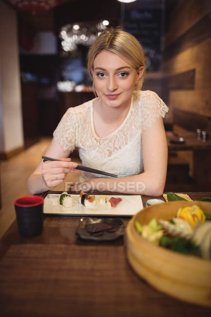 Retrato de mulher sorridente comendo sushi em restaurante — Fotografia de Stock