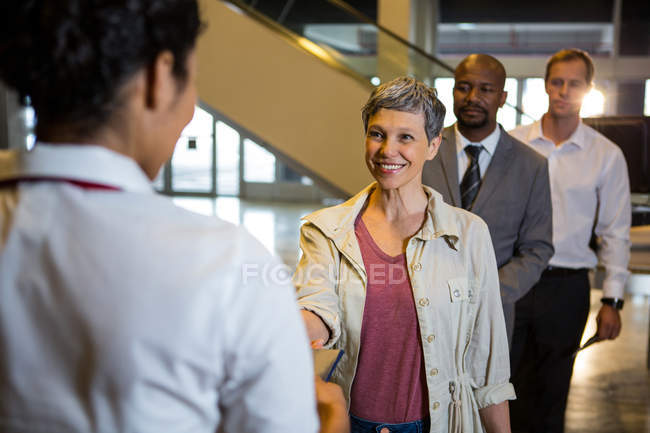 Woman handing over her boarding pass to the female staff at airport terminal — Stock Photo