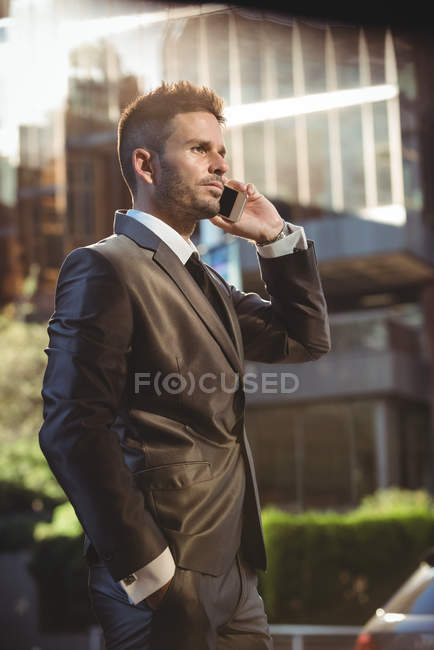 Businessman talking on mobile phone on urban street — Stock Photo