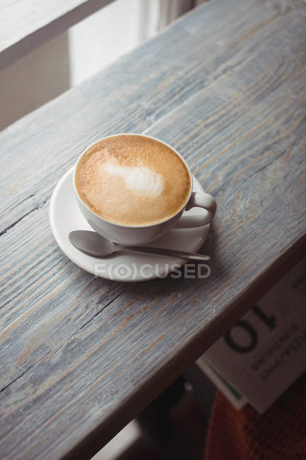 Close-up of cup of coffee and spoon on wooden table — Stock Photo