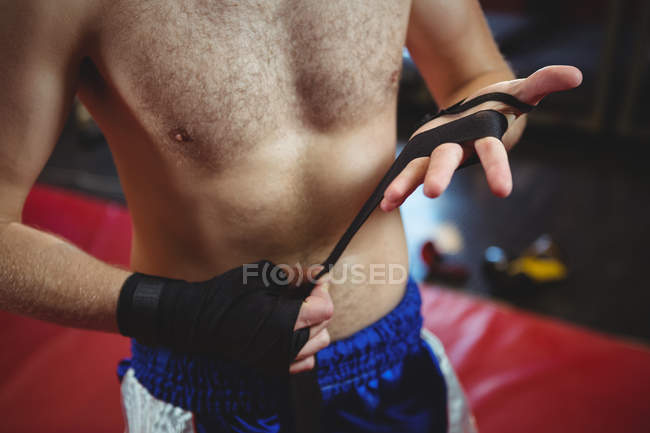 Средняя секция боксера, носящего черный ремень на запястье в фитнес-студии — стоковое фото