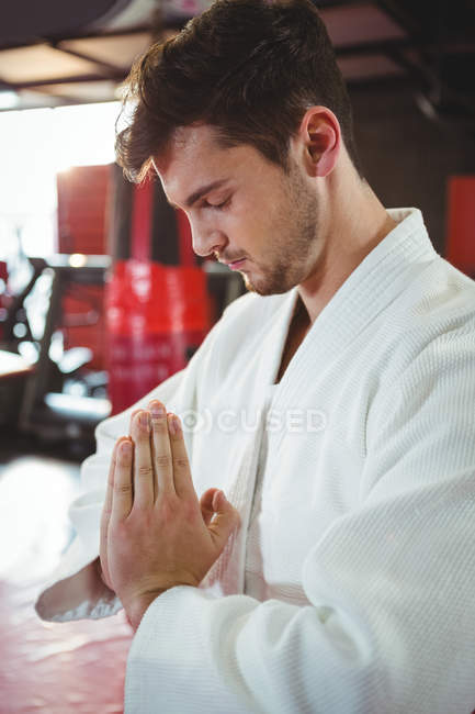 Joueur de karaté en prière pose dans un studio de fitness — Photo de stock