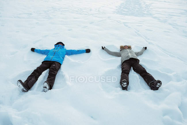 Casal deitado na neve paisagem coberta — Fotografia de Stock