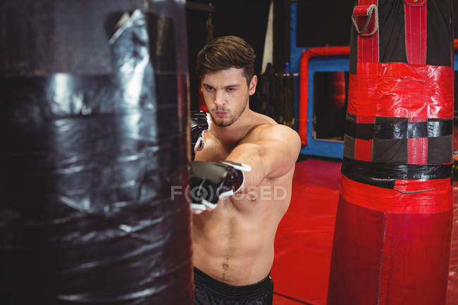 Boxer perfurando saco de boxe no estúdio de fitness — Fotografia de Stock
