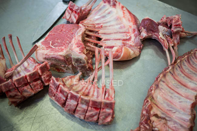 Primer plano de costillas de carne y cuchillo en mesa metálica - foto de stock