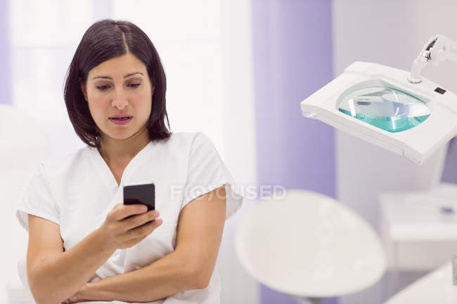 Dermatologista usando telefone celular na clínica — Fotografia de Stock