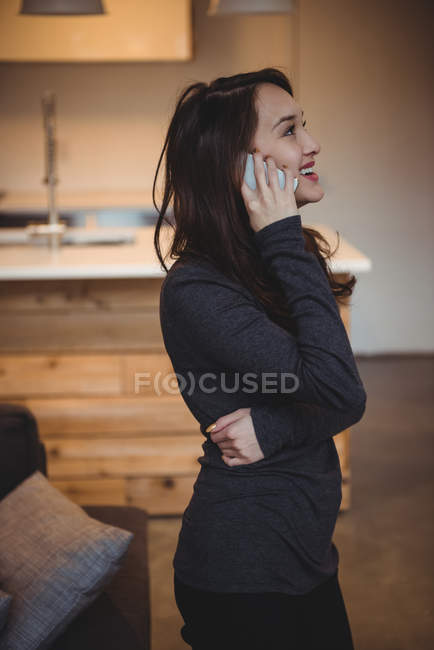 Woman talking on mobile phone in living room at home — Stock Photo
