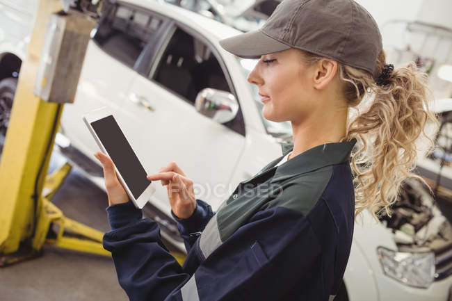 Female mechanic using digital tablet in repair shop — Stock Photo