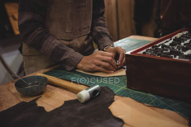 Mittelteil einer Kunsthandwerkerin, die in der Werkstatt an einem Stück Leder arbeitet — Stockfoto