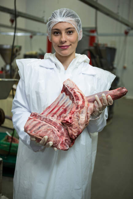 Porträt einer Metzgerin, die Fleisch in einer Fleischfabrik hält — Stockfoto
