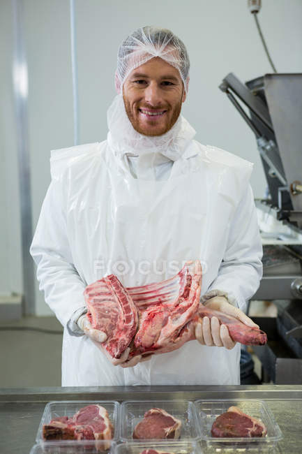 Портрет м'ясника, що тримає сире м'ясо на м'ясному заводі — стокове фото