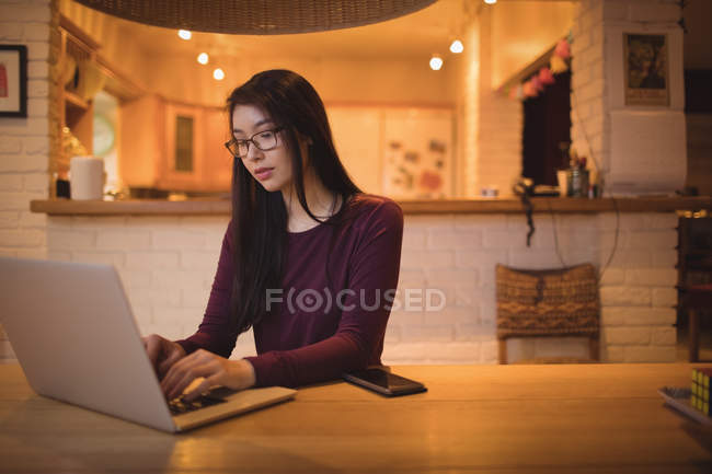 Femme utilisant un ordinateur portable sur la table dans le salon à la maison — Photo de stock