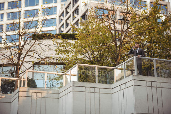 Empresário falando no celular perto do prédio de escritórios — Fotografia de Stock