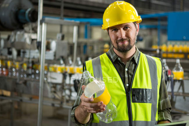 Portrait of confident male worker inspecting bottles in juice factory — Stock Photo