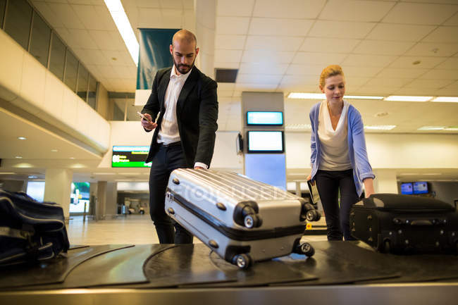 Pendler, die am Flughafen ihr Gepäck vom Gepäckband nehmen — Stockfoto