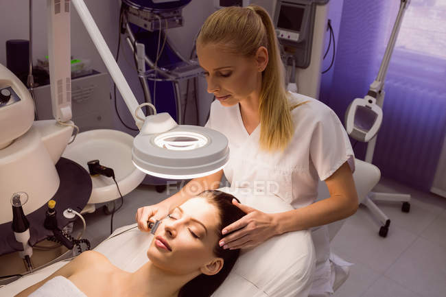 Dermatologista feminina realizando depilação a laser no rosto do paciente na clínica — Fotografia de Stock