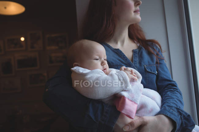 Madre sosteniendo lindo bebé en brazos en la cafetería - foto de stock