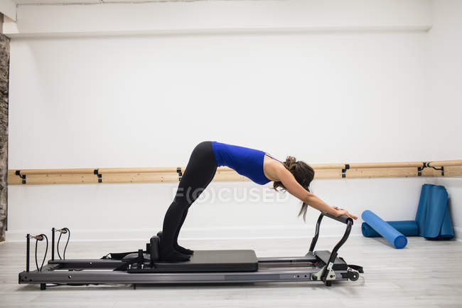 Femme faisant de l'exercice sur le réformateur dans un club de santé — Photo de stock