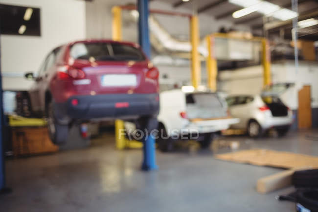Автомобиль на гидравлическом подъемнике в ремонтном гараже — стоковое фото