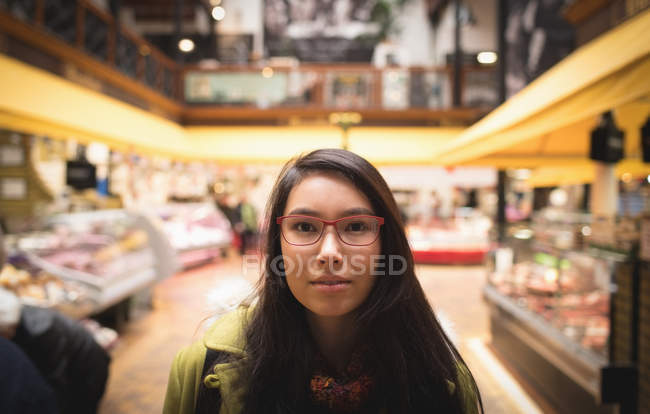 Portrait de femme avec des lunettes debout dans un supermarché — Photo de stock