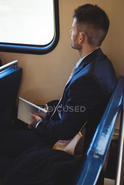 Geschäftsmann mit digitalem Tablet und Paket im Zug unterwegs — Stockfoto