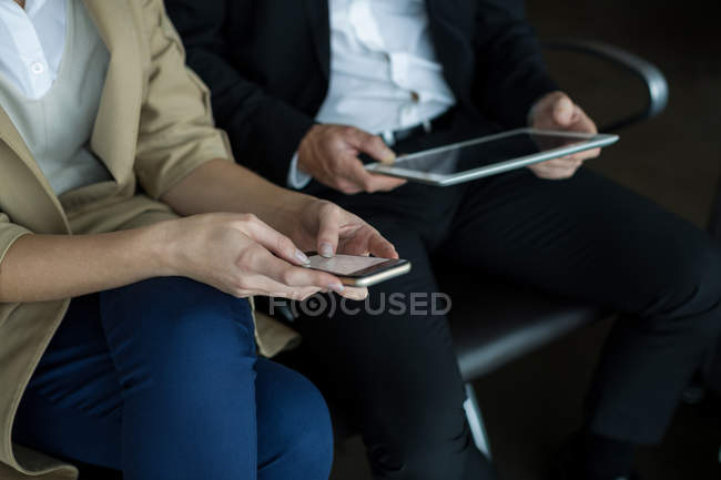 Mittelteil des Paares nutzt Handy und digitales Tablet am Flughafen — Stockfoto