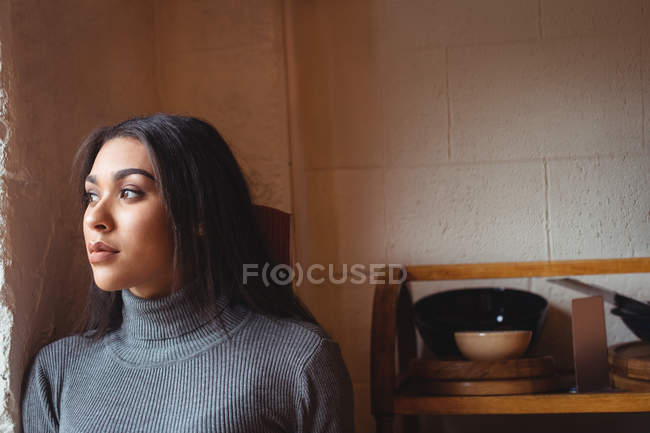 Задумчивая женщина, прислонившаяся к стене кафе — стоковое фото