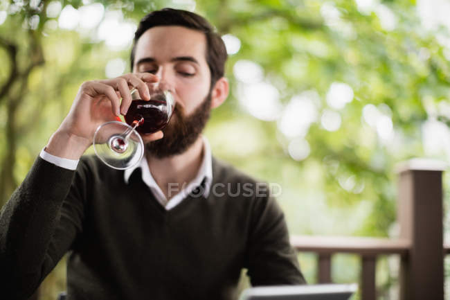 Homem usando tablet digital enquanto toma um copo de vinho no bar — Fotografia de Stock