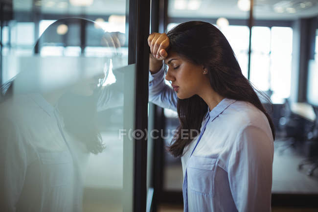 Femme d'affaires énervée appuyé contre la porte dans le bureau — Photo de stock
