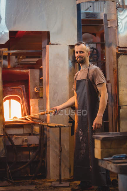 Portrait of glassblower heating glass in glassblowers oven at glassblowing factory — Stock Photo