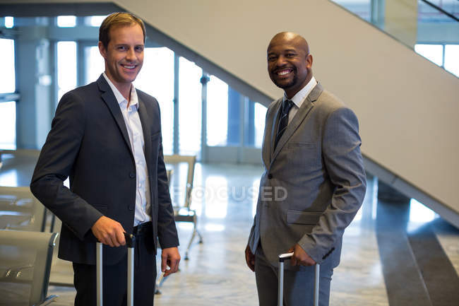 Portrait of business people standing with luggage bag in airport — Stock Photo