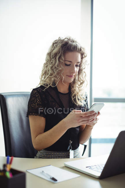 Деловая женщина с помощью мобильного телефона в офисе — стоковое фото