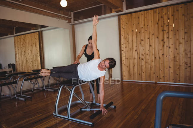 Coach helping woman practicing pilates in fitness studio — Stock Photo